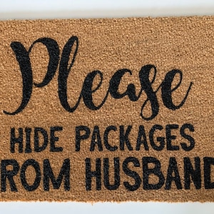 May include: A brown coir doormat with the text "Please hide packages from husband" in black lettering.