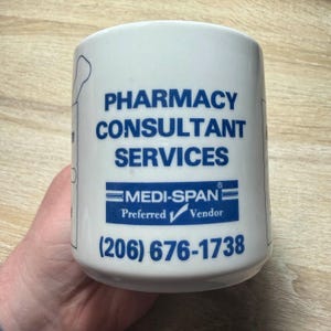 May include: White ceramic mug with blue text that reads "Pharmacy Consultant Services" and "Medi-Span Preferred Vendor" with a phone number (206) 676-1738.