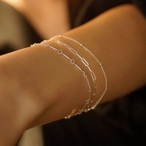 Three-piece bracelet set with a sterling silver bar bracelet, a 2mm paperclip bracelet, and a thin satellite bracelet.