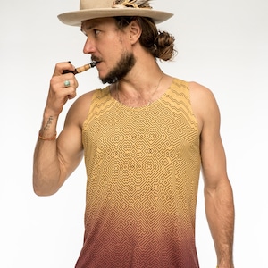 Può includere: Un uomo con un cappello marrone con piume, una canotta con stampa geometrica gialla e rossa e una pipa in bocca.