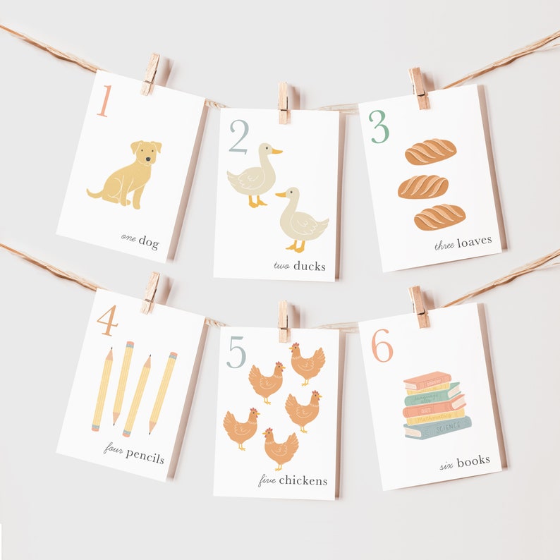 May include: Six cards with numbers 1 through 6, each with a different illustration and a corresponding word. The illustrations include a dog, ducks, loaves of bread, pencils, chickens, and books.