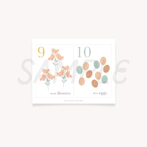 May include: A printable educational chart with two sections. The left side shows nine pink flowers with yellow centers and the number nine. The right side shows ten eggs in various shades of brown and blue and the number ten. The text below the flowers reads "nine flowers" and the text below the eggs reads "ten eggs".