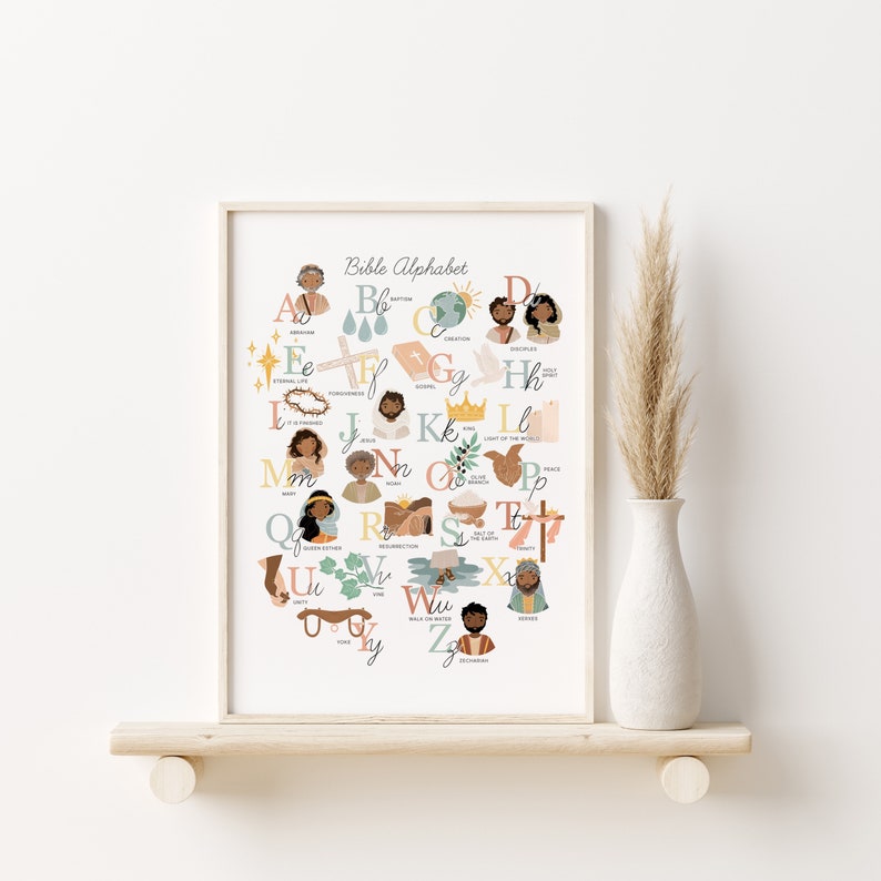 May include: A framed print titled "Bible Alphabet" featuring colorful illustrations for each letter. The artwork includes images of people, religious symbols, and text. The print is displayed on a wooden shelf with a white vase and decorative grass.