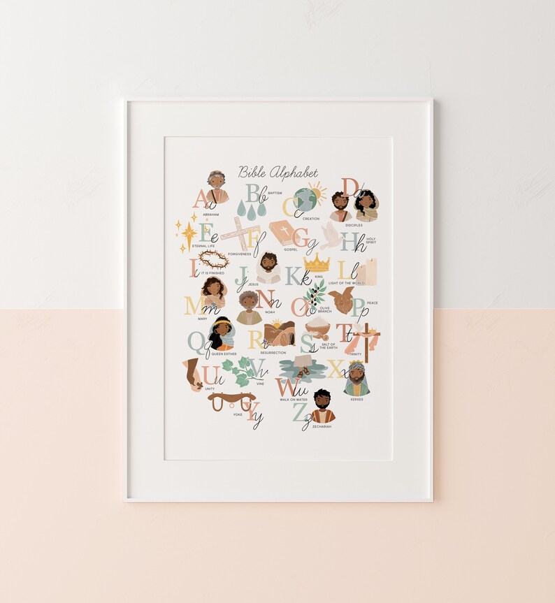 May include: A framed print featuring the "Bible Alphabet" in a colorful, illustrated style. Each letter is paired with a biblical figure or symbol, such as Abraham, Creation, and Jesus. The artwork is set against a two-tone pink and white background.