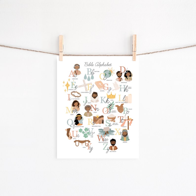 May include: A white print titled "Bible Alphabet" featuring illustrated letters with corresponding biblical words and images. The print is held by wooden clothespins on a string against a white background. The illustrations include people, crosses, and other religious symbols.