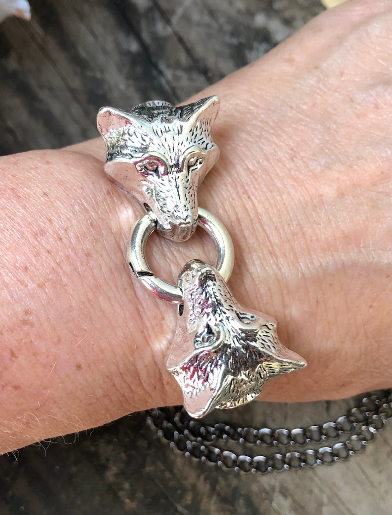 May include: Silver bracelet with two wolf head charms. The bracelet is made of a chain link design.