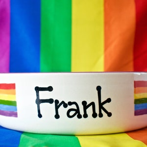 May include: White ceramic pet bowl with a rainbow design and the name "Frank" written in black.