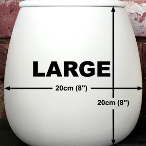 May include: White ceramic planter with the word "LARGE" printed on the front. The planter is 8 inches in diameter and 8 inches tall.