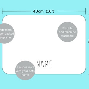May include: White personalized pet feeding mat with gray text that says "NAME" and "Personalised with your pets name". The mat is made from rubber-backed neoprene and is flexible and machine washable. The mat measures 16 inches by 11 inches.