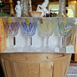 Puede incluir: Conjunto de cuatro vasos de chupito de vidrio transparente con diseños coloridos. Cada vaso tiene un diseño de color diferente: morado, azul, amarillo y verde. Los vasos están en una caja blanca con el texto "Francia" y "Hecho en Francia" en la etiqueta.