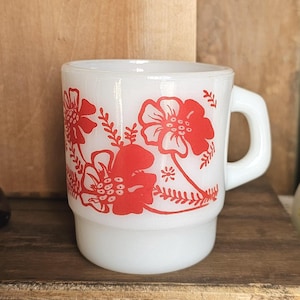 Puede incluir: Taza de cerámica blanca con un diseño floral rojo. Las flores son estilizadas y tienen un aspecto vintage.