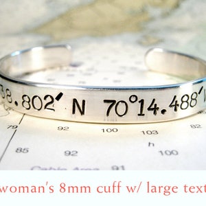 May include: Silver cuff bracelet with the coordinates 38.802' N 70°14.488' W engraved in large text.