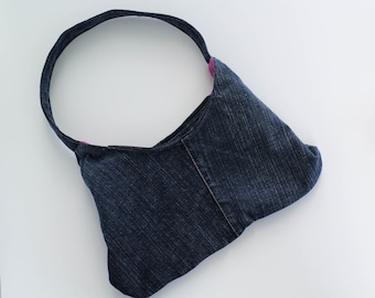 May include: A blue denim tote bag with a pink fabric strap. The bag is on a white surface.