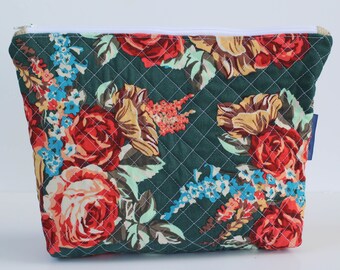 May include: A green quilted zippered pouch with a floral print featuring red, pink, and yellow roses, blue and white flowers, and green leaves.