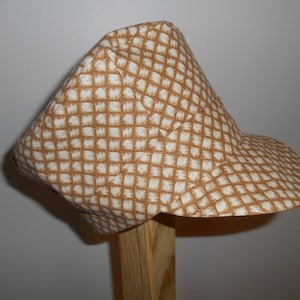 May include: A brown and white patterned fabric hat with a short brim. The hat is made of a soft, comfortable material and has a casual, relaxed style.