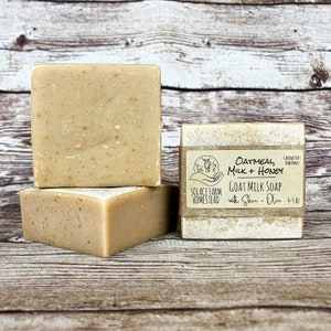 K&ouml;nnte beinhalten: Drei St&uuml;ck Ziegenmilchseife &uuml;bereinander gestapelt. Die oberste Seife hat ein Etikett mit der Aufschrift "Oatmeal, Milk + Honey Goat Milk Soap with Shea + Olive 4-5 oz. Ground Oats Raw Honey Solace Farm Homestead".