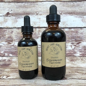 May include: Two amber glass bottles with dropper tops, labeled "Solace Farm Homestead Handmade Elderberry Tincture". The smaller bottle is 2 oz and the larger bottle is 4 oz.