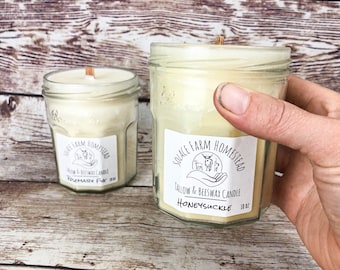 May include: Two glass jars with white labels and wooden wicks. The labels read "Solace Farm Homestead Tallow & Beeswax Candle" with the scents "Rosemary Fir" and "Honeysuckle".
