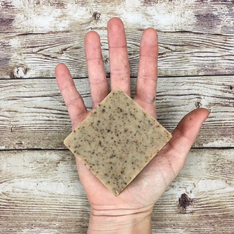 Puede incluir: Una pastilla de jab&oacute;n cuadrada de color marr&oacute;n y beige moteado. El jab&oacute;n est&aacute; en la palma de una mano.