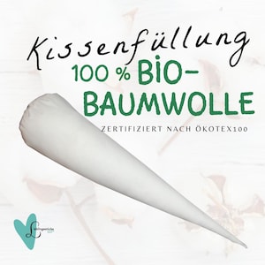 Könnte beinhalten: Weisse Baumwoll-Kissenfüllung in Kegelform. Das Etikett lautet "Kissenfüllung 100% Bio-Baumwolle ZERTIFIZERT NACH ÖKOTEX100".