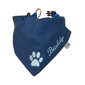 Könnte beinhalten: Blaues Hundehalstuch mit einem Pfotenabdruck und dem Namen "Buddy" bestickt.