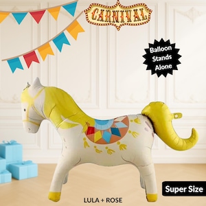 Puede incluir: Un gran globo con forma de caballo blanco y amarillo con un diseño colorido. El globo tiene una melena y cola amarillas, y el texto "LULA + ROSE" y "Super Size" son visibles. La palabra "CARNIVAL" se muestra encima del globo.