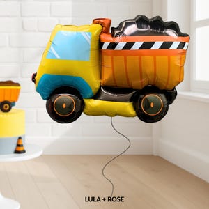 May include: A yellow, blue, and orange dump truck balloon with black wheels and a black and white striped bed. The balloon has a gray string attached. The text "LULA + ROSE" is at the bottom.