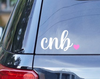 May include: White vinyl decal with the text "cnb" in cursive lettering and a pink heart.