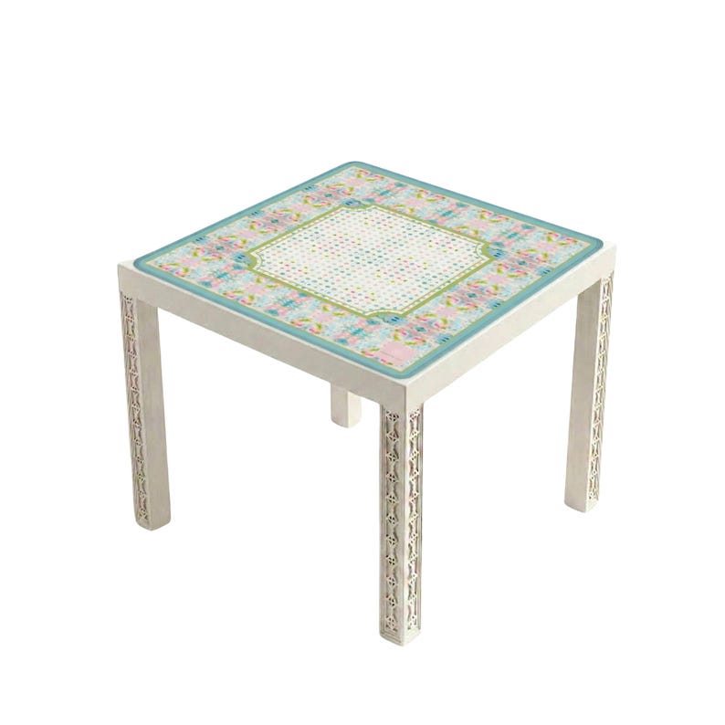 May include: A square side table with off-white legs featuring intricate vertical cut-out patterns. The tabletop has a central white grid panel surrounded by a border of light blue, pink, and green floral patterns with a teal edge trim.