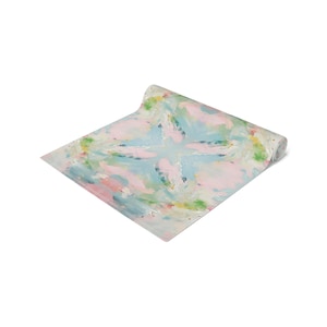 May include: Rolled-up yoga mat with an abstract watercolor design. The pattern features soft pastel colors, including pink, blue, and green, creating a calming and artistic aesthetic. The mat is designed for exercise and relaxation.