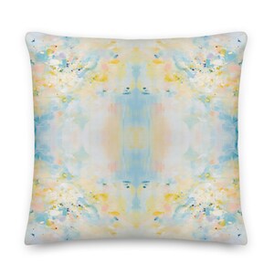 May include: A square throw pillow with an abstract design featuring shades of blue, yellow, and pink. The design is symmetrical and has a watercolor-like effect.