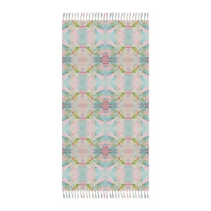 May include: A pink and blue patterned throw rug with fringe on the ends. The rug has a geometric design with a repeating pattern.