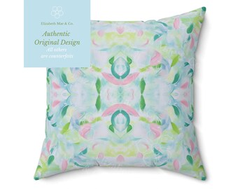May include: A square throw pillow featuring a symmetrical abstract pattern with soft brushstrokes in shades of light blue, mint green, and pale pink on a white background. The design creates a mirrored effect across the center of the pillow.