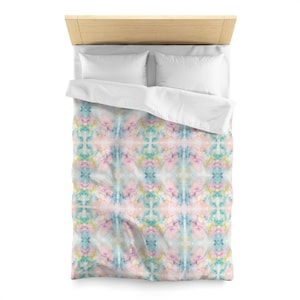 May include: A white duvet cover with a colorful abstract pattern. The pattern features shades of pink, blue, and green in a watercolor-like style. The duvet cover is made of soft, breathable fabric and is perfect for adding a touch of color and style to any bedroom.