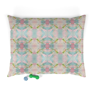 May include: Rectangular pet bed with a colorful abstract pattern in shades of pink, blue, and green. A small blue ball and a green dumbbell-shaped toy are at the bottom of the bed.