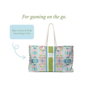 May include: A tote bag featuring a blue, green, and pink abstract floral pattern with a central vertical green stripe and white rope handles. The text "For gaming on the go." appears above, and a box labels it "Blue, Green & Pink Snowdrops Tote".