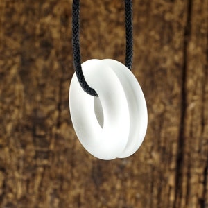以下が含まれることがあります： 黒い紐に、白のセラミック製のペンダントがぶら下がっています。ペンダントは2つの輪が絡み合っており、滑らかで光沢のある仕上げになっています。