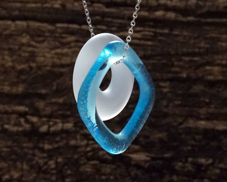 May include: A necklace with a blue and white glass pendant. The pendant is shaped like a figure eight, with the blue glass forming the outer loop and the white glass forming the inner loop.