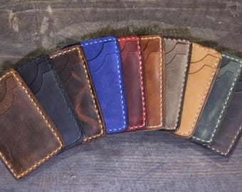 May include: A variety of leather card holders in different colors, including brown, black, blue, red, and green. The card holders are all made of high-quality leather and have a minimalist design.