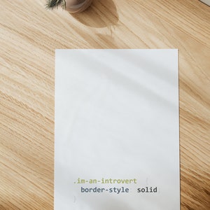 K&ouml;nnte beinhalten: Ein wei&szlig;es Blatt Papier mit dem Text ".im-an-introvert { border-style: solid; }" darauf. Das Papier liegt auf einer hellbraunen Holzoberfl&auml;che.