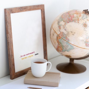 Peut inclure: Une tasse en c&eacute;ramique blanche avec un cadre en bois brun et un globe sur une &eacute;tag&egrave;re blanche. La tasse est remplie d'un liquide brun et le cadre porte le texte ".im-an-extrovert border-style: none" &eacute;crit dessus.
