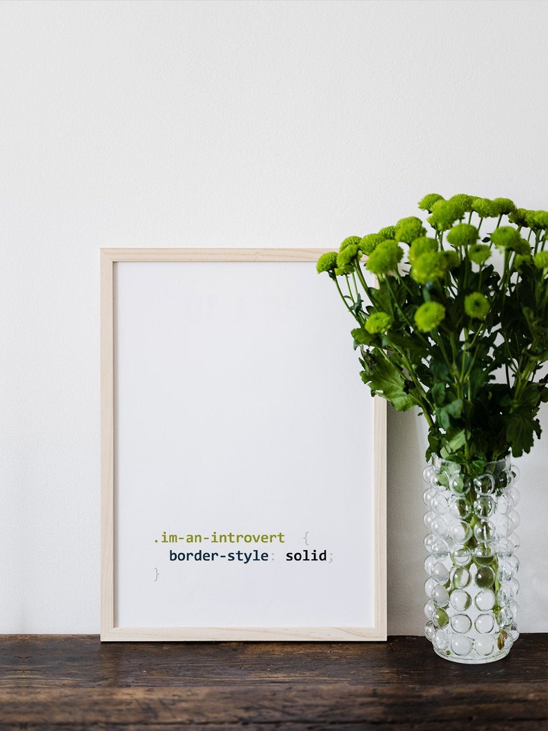 K&ouml;nnte beinhalten: Ein gerahmter Druck mit dem Text ".im-an-introvert { border-style: solid; }" in einer hellgr&uuml;nen und dunkelgr&uuml;nen Schriftart. Der Druck steht auf einem Holztisch neben einer durchsichtigen Glasvase mit gr&uuml;nen Blumen.