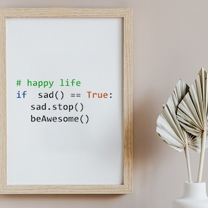 Op de afbeelding: Een ingelijste print met de tekst "# happy life" in het groen, gevolgd door een codefragment. De code luidt "if sad() == True: sad.stop() beAwesome()". De lijst is lichtbruin en de achtergrond is neutraal. Een witte vaas met gedroogde planten staat op de voorgrond.