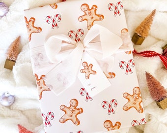 May include: White gift wrap with a gingerbread man and candy cane pattern. The gift is tied with a white ribbon and a gift tag that says "To: from:"