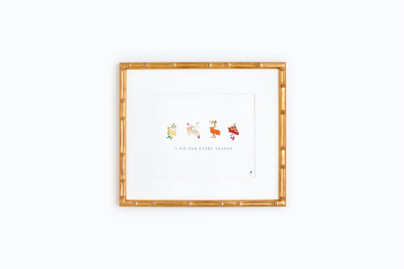 Puede incluir: Una impresi&oacute;n enmarcada con fondo blanco y marco dorado. La impresi&oacute;n presenta una l&iacute;nea de cuatro porciones de pastel, cada una con un relleno diferente y un peque&ntilde;o dise&ntilde;o floral. El texto "A PIE FOR EVERY SEASON" est&aacute; impreso debajo de los pasteles.