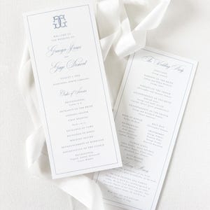 May include: Two white wedding program cards with blue text and a blue monogram at the top. The left card lists the order of service for Gracyn Jones and Gage Dement on August 3, 2024. The right card lists the wedding party. A white ribbon is draped.