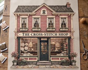 May include: A cross-stitch pattern on fabric depicting a two-story building with a storefront labeled THE CROSS-STITCH SHOP. The design features a red facade, dark green trim, windows with white curtains, and flower boxes. Embroidery floss and scissors are nearby.
