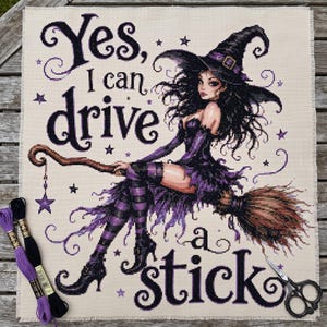 May include: A cross-stitch embroidery piece on cream fabric featuring a witch with long black hair and a purple outfit riding a broomstick. The text reads, Yes, I can drive a stick, surrounded by purple stars. Includes two embroidery floss skeins and scissors.
