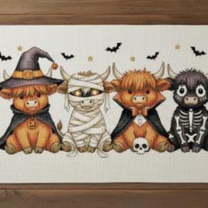 May include: A cross-stitch design showing four Highland cows in Halloween costumes. One wears a witch's hat and cape, another is a mummy, a third a vampire, and the last a skeleton. Bats and stars are also stitched into the design.