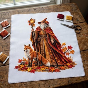 May include: A cross-stitch pattern on white fabric featuring a bearded wizard in a long red and gold robe with a matching hat, holding a staff topped with a glowing orb. A red fox stands beside the wizard amidst fallen autumn leaves.